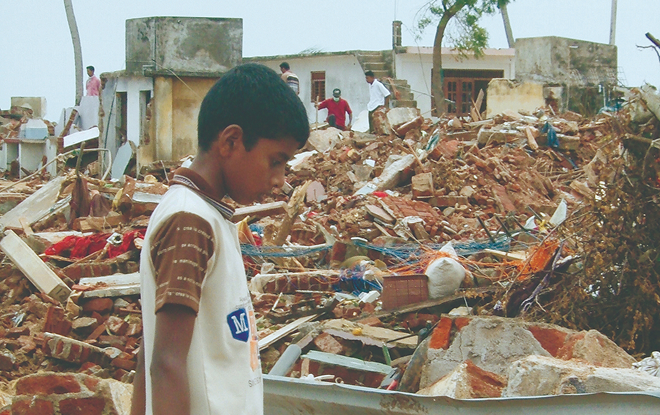 A solitary boy picks his way through the rubble of destroyed buildings.